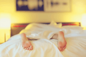 woman lying on a bed with crisp white sheets in a blurred background