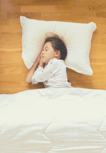 young girl sleeping on a hard wood floor