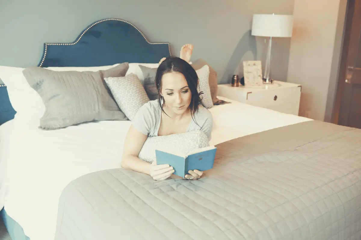 brunette woman reading a book in bed